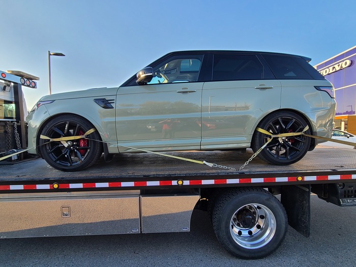 Flatbed tow truck towing a landrover