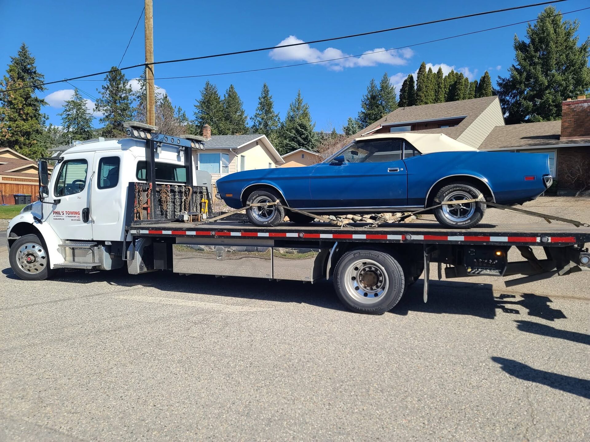 A classic car loaded on Phil's Towing flat deck tow truck